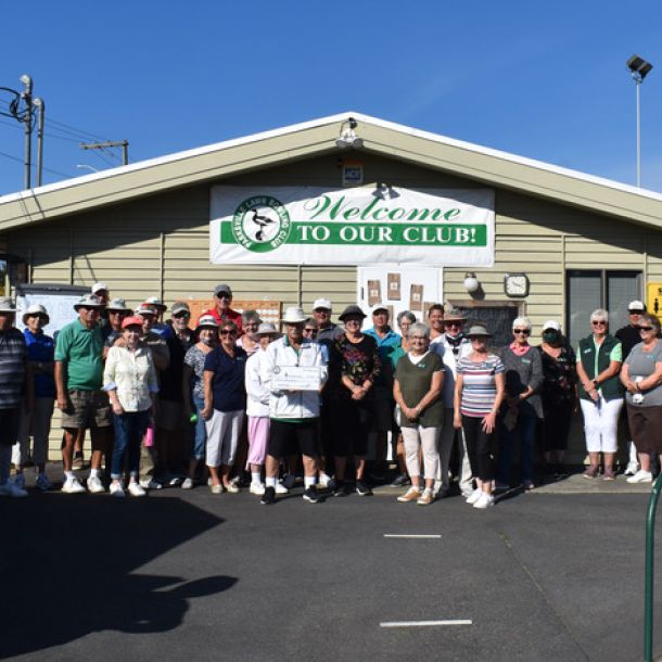 Parksville Lawn Bowling Club group photo by clubhouse with sign that says 'welcome to our club'