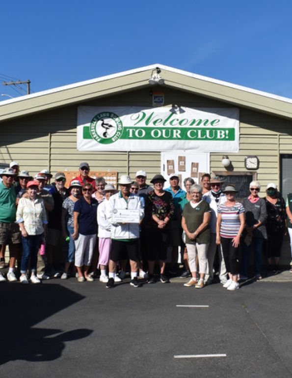 Parksville Lawn Bowling Club group photo by clubhouse with sign that says 'welcome to our club'