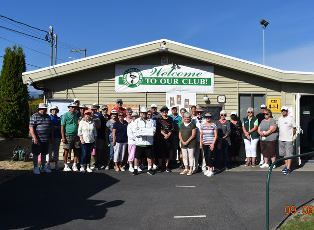 Parksville Lawn Bowling Club posing by building, welcome to our club sign and blue skies in the background